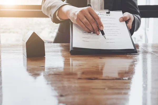 Ondertekening contract. Close-up van zelfverzekerde jonge man ondertekening van een document, terwijl een andere man in overhemd en stropdas zitten dicht bij hem en wijzen van document — Stockfoto