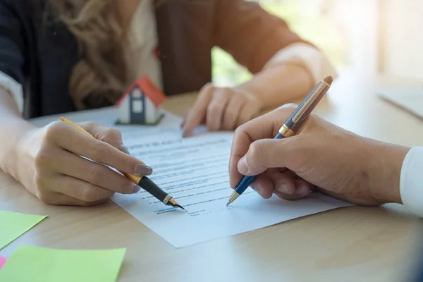 Client signant un contrat immobilier en agence immobilière avec modèle de maison — Photo