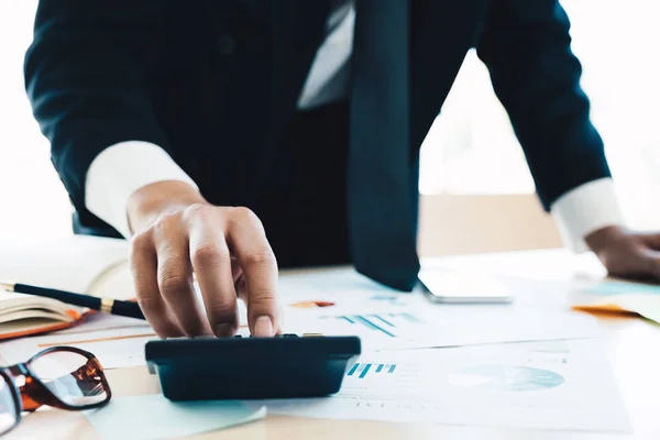 Gros plan d'un homme d'affaires ou d'un comptable tenant un stylo à main travaillant sur une calculatrice pour calculer les données de l'entreprise, un document comptable et un ordinateur portable au bureau, concept d'entreprise — Photo