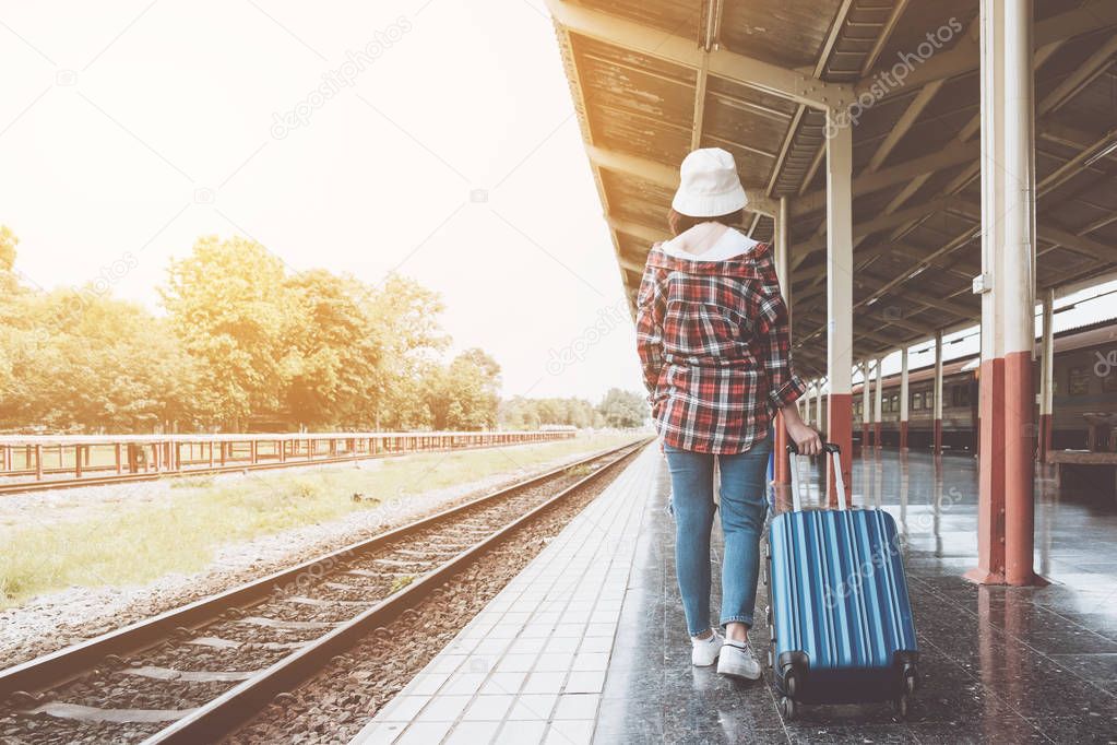 Young hipster girl with luggage at station traveling by train, Travel concept