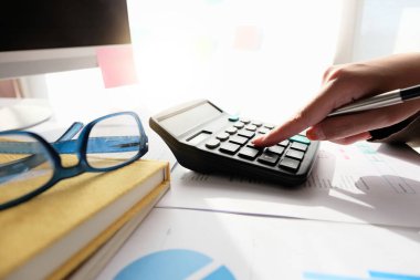 Muhasebeciyi merkez ofisteki mali giderleri hesaplamak için hesap makinesi kullanarak kapat