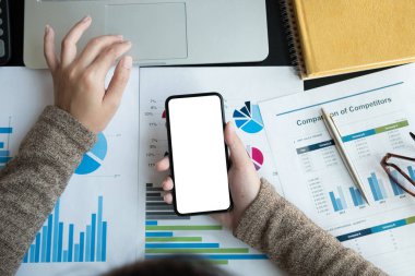 Beyaz ekranlı akıllı telefon ve muhasebe ve finans için dizüstü bilgisayar kullanan iş kadınlarının en iyi görüntüsü, evde çalışıyor