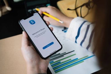 CHIANG MAI, THAILAND - APR 06, 2020: Skype uygulamalı iPhone X 'leri tutan kadın, Skype Microsoft' un bir parçası, video, ses görüşmeleri, sohbet mesajları yapabiliyor ve Skype 'ı kullanarak daha fazlasını yapabiliyor.