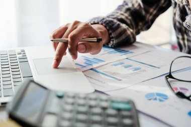 İşadamı ya da muhasebeci, ofiste finansal aksesuar hesaplamak için dizüstü bilgisayarla çalışıyor.