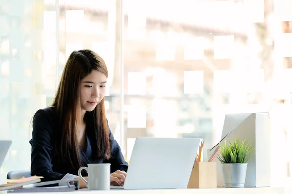 Красивая молодая азиатка работает в современном офисе с ноутбуком для делового финансового анализа — стоковое фото