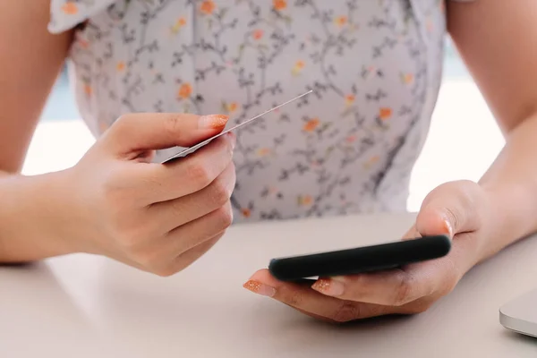 Закройте руку женщине, пользующейся смартфоном и держащей кредитную карту для онлайн-покупок — стоковое фото