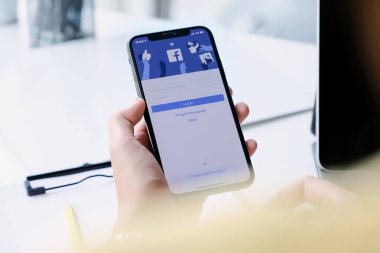 CHIANG MAI, THAILAND - 7 MAR 2020: Yeni giriş ekranlı facebook kullanmak için kadın el ele tutuşma iPhone XS.