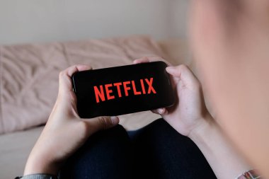 CHIANG MAI, THAILAND, MAR 29, 2020: Evde Apple iPhone X üzerinde Netflix logosu olan akıllı telefonu tutan kadın. 