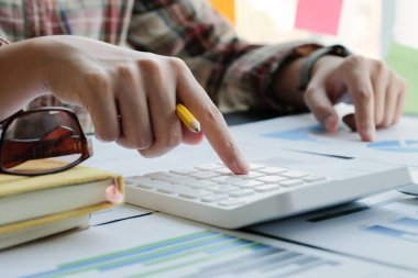 Finans ve muhasebe alanında çalışan iş kadını, mali bütçeyi hesap makinesiyle analiz eder 