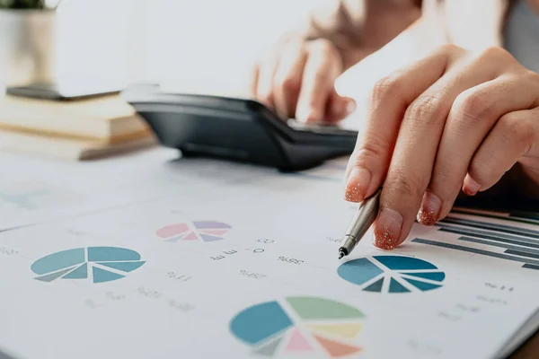 Close-up de mulher de negócios ou contador usando calculadora durante a análise em papel de dados — Fotografia de Stock