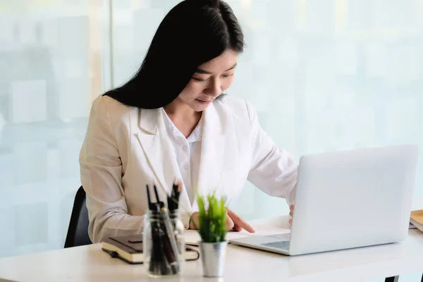 Menina asiática bonita trabalhando no escritório moderno com um computador portátil para análise financeira de negócios — Fotografia de Stock
