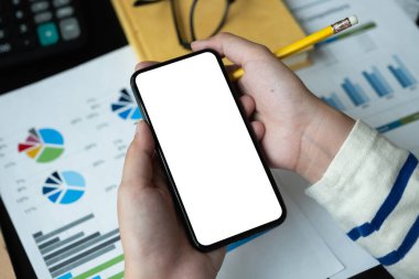 Muhasebe için karanlık modaya uygun çalışma alanında elinde boş ekranlı akıllı telefon tutan kadının üst görüntüsü
