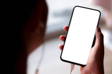 Kafede kulaklıklı akıllı telefon kullanan bir kadının elini kapat..