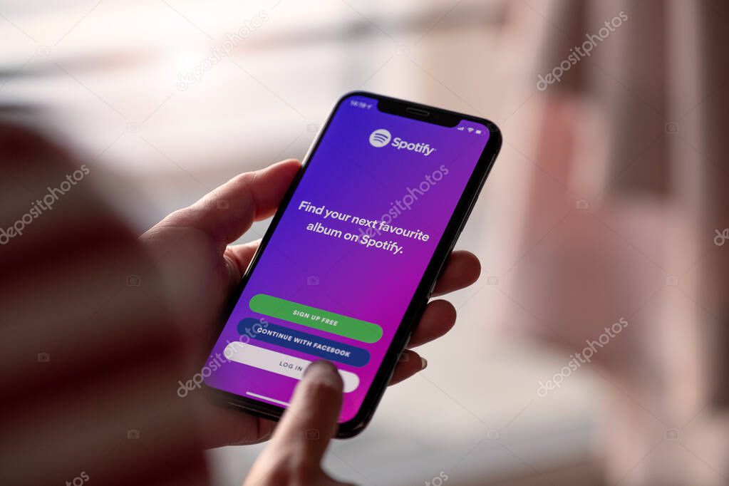 CHIANG MAI, THAILAND - NOV 17 2019: Person holding a brand new Apple iPhone XS with Spotify logo on the screen. Spotify is a popular commercial music streaming service.