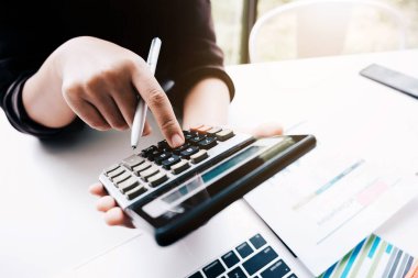 Hesap makinesi kullanarak ahşap masa üzerinde matematik finansmanı yapan iş kadını kapat.