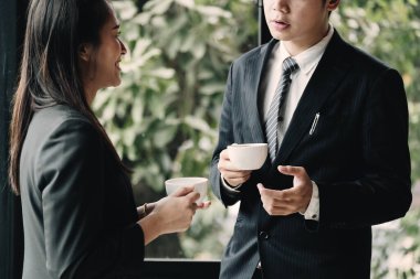 Kahve molası. Grup çalışanları, modern ofiste, ellerinde fincanlarla, pencerenin önünde sırıtarak duruyorlar.