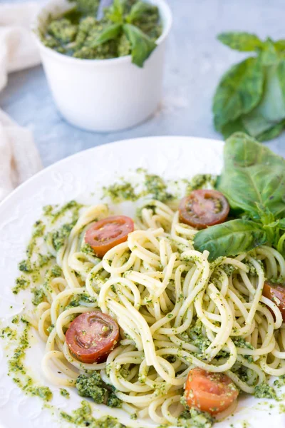 Healthy dinner with the Italian paste spaghetti and green pesto sauce with a basil