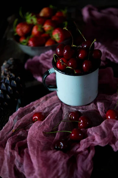 Summer red berries on a season. Red sweet cherry in a vintage iron plate on a wooden table. A still life from red summer berries