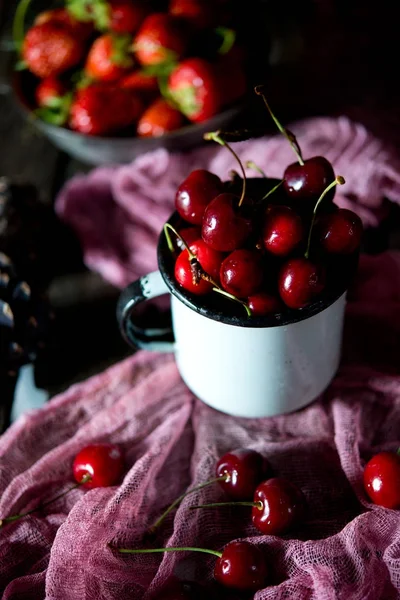 Summer red berries on a season. Red sweet cherry in a vintage iron plate on a wooden table. A still life from red summer berries