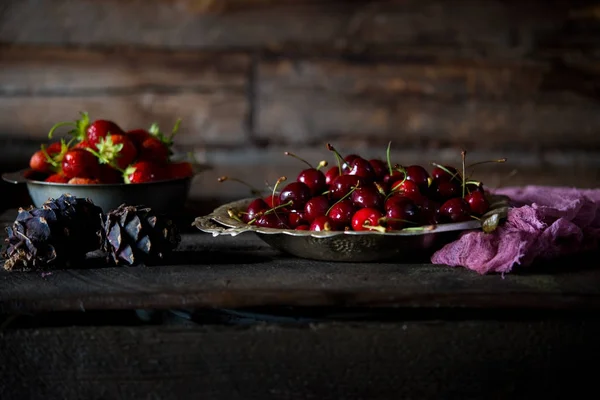 A set of summer red berries on a season. Red strawberry and sweet cherry on a wooden table. A still life from red summer berries.