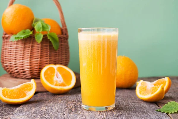 A glass of freshly squeezed juice surrounded by fresh oranges and tangerines. Horizontal photo.