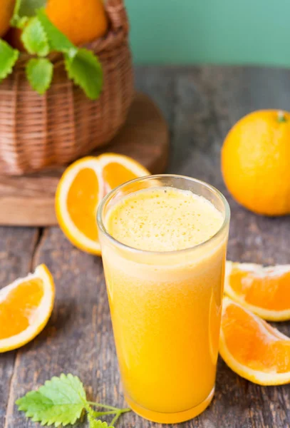 A glass of freshly squeezed juice surrounded by fresh oranges and tangerines. Vertical photo.