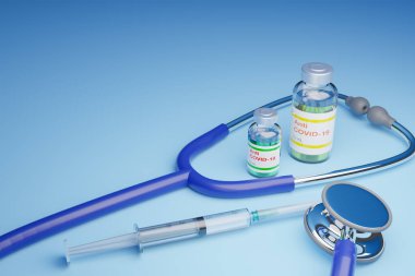 3 boyutlu şırınga, COVID-19 aşı şişesi ve steteskop mavi masanın üstünde.