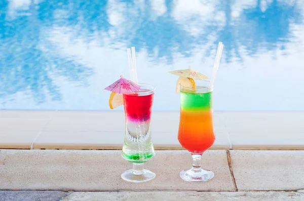 Colored cocktails on a background of water. Colorful cocktails near the pool. Beach party. Summer drinks. Exotic drinks. Glasses of cocktails on table near pool. Summer drinks photo concept. ocktail — Stock Photo, Image