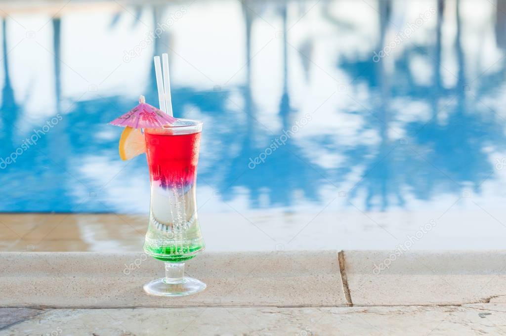 Colored cocktails on a background of water. Colorful cocktails near the pool. Beach party. Summer drinks. Exotic drinks. Glasses of cocktails on table near pool. Summer drinks photo concept. ocktail