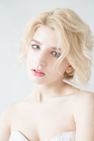 Женщина с белыми волосами в свадебном платье. Молодая блондинка с голубыми глазами. Портрет красивой блондинки. Модель моды. Женщина с идеальной кожей. Наголый макияж. Концепция модной фотографии
