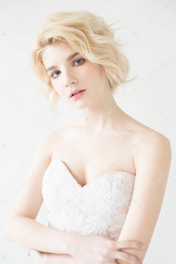 Woman with white hair in a wedding dress. Young blonde woman with blue eyes. Portrait of a beautiful blonde girl. Fashion model. Woman with perfect skin. Nude makeup. Fashion photography concept