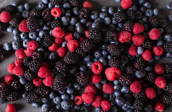 Raspberries, blackberries, blueberries a gray abstract background