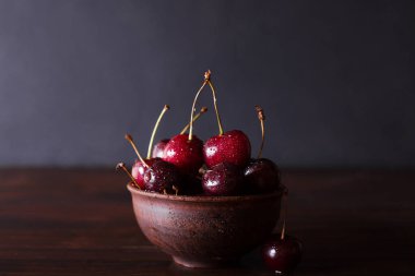Kiraz. Kiraz. Seramik kase kiraz. Kırmızı Kiraz. Taze kiraz. Kiraz koyu arka plan üzerinde. sağlıklı gıda kavramı. Kiraz ile su damlaları