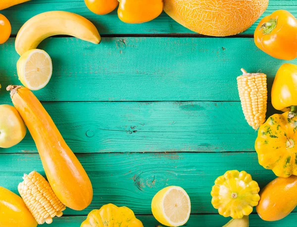 Yellow fruits and vegetables on a turquoise wooden background. Colorful festive still life. Copyspace. Yellow squash, melon, lemon, banana, pepper, apples, corn — Stock Photo, Image