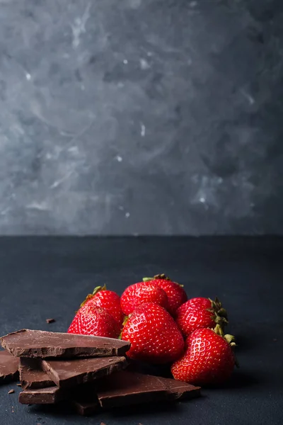 Клубника с ломтиками шоколада на тёмном фоне — стоковое фото