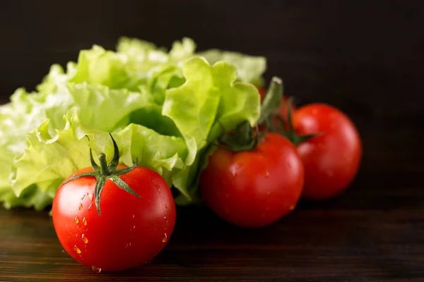 Tomatoes and lettuce on a wooden background — Stock Photo, Image