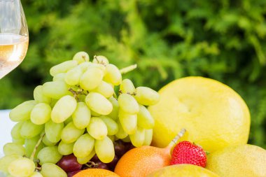 bir tabak ve bardağı taze meyve bahçesinde bir masada beyaz şarap ile