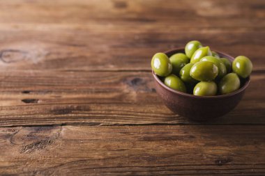 Yeşil zeytin ahşap arka plan üzerinde bir seramik kase. Zeytin arka plan. Yeşil Zeytin ile arka plan. Zeytin. Boşaltmak