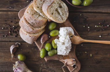 Yeşil Zeytin, ciabatta, ahşap bir tahta üzerinde beyaz peynir dilimlenmiş. Baharat. Sarımsak. Chees beyaz. Ciabatta. Zeytin ahşap arka plan üzerinde. Boşaltmak