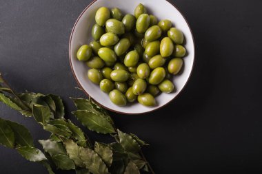 Yeşil Zeytin siyah bir zemin üzerine beyaz bir kase. Zeytin arka plan. Yeşil Zeytin ile arka plan. Zeytin. Defne yaprağı.