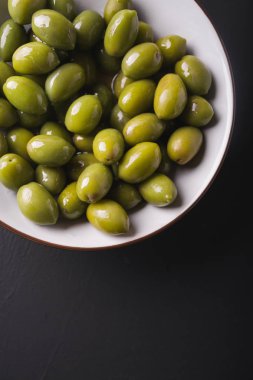 Yeşil Zeytin siyah bir zemin üzerine beyaz bir kase. Zeytin arka plan. Arka plan yeşil zeytin ile.