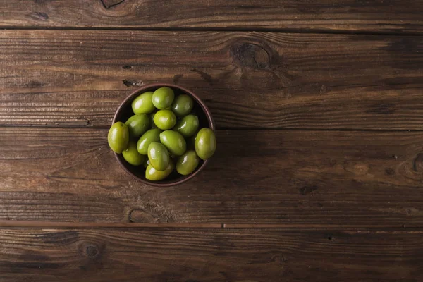 Olive verdi in una ciotola di ceramica su fondo di legno. Contesto delle olive. Sfondo con olive verdi. Olive. Copyspace — Foto Stock