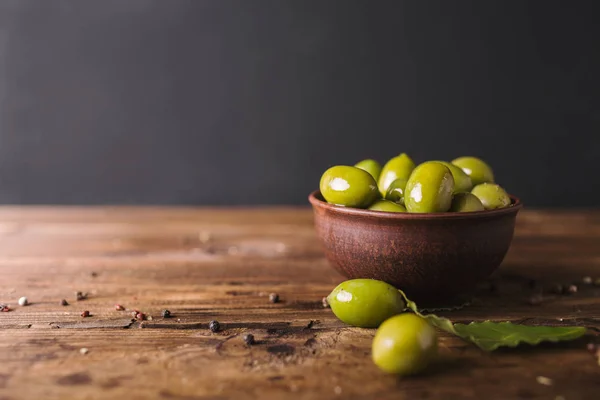 Зеленые оливки, лавровый лист на деревянной доске . — стоковое фото