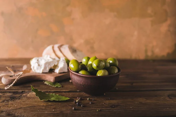 Aceitunas verdes, ciabatta en rodajas, queso feta en una tabla de madera. Con especias. Queso Feta . — Foto de Stock