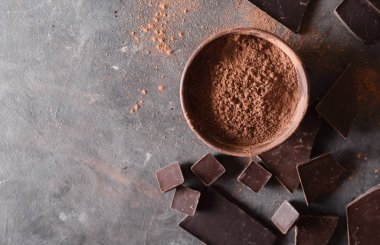 Çikolata parçaları ve kakao tozu. Çikolata parçaları bar. Çikolata gri arka plan üzerinde büyük bir bar. Çikolata ile arka plan. Çikolata dilim,