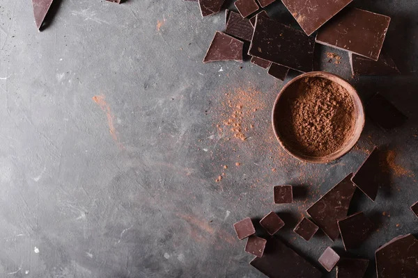 Шоколадные кусочки и какао-порошок. Шоколадные кусочки. Большая плитка шоколада на сером абстрактном фоне. Фон с шоколадом. Кусочки шоколада , — стоковое фото