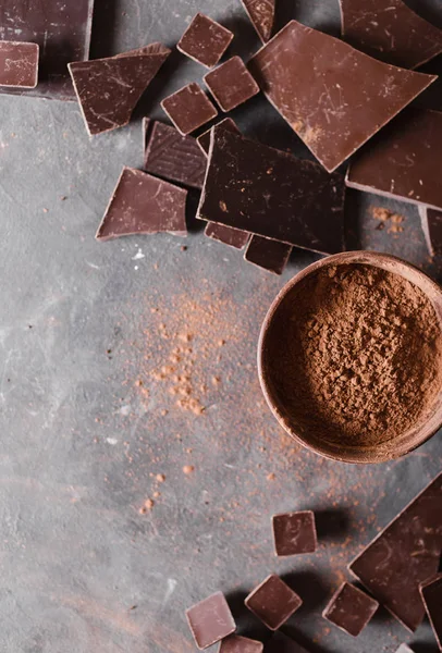 Chocolate  chunks and cocoa powder. Chocolate bar pieces.  A large bar of chocolate on gray abstract background. Background with chocolate. Slices of chocolate,