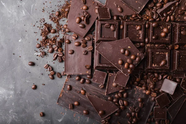 Kaffeebohnen mit dunkler Schokolade. Scherben von Schokolade. Schokoriegel. eine große Tafel Schokolade auf grauem abstrakten Hintergrund. Kaffeebohnen. — Stockfoto