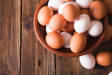 Bir seramik kase ahşap arka plan üzerinde beyaz ve kahverengi yumurta. Rustik tarzı. Yumurta. Paskalya fotoğraf kavramı. Boşaltmak 