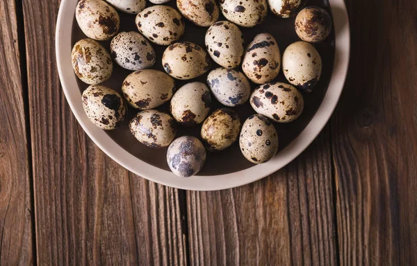 Huevos de codorniz en un plato marrón sobre una mesa de madera. Estilo rústico. Huevos. Concepto de foto de Pascua. Espacio de copia — Foto de Stock